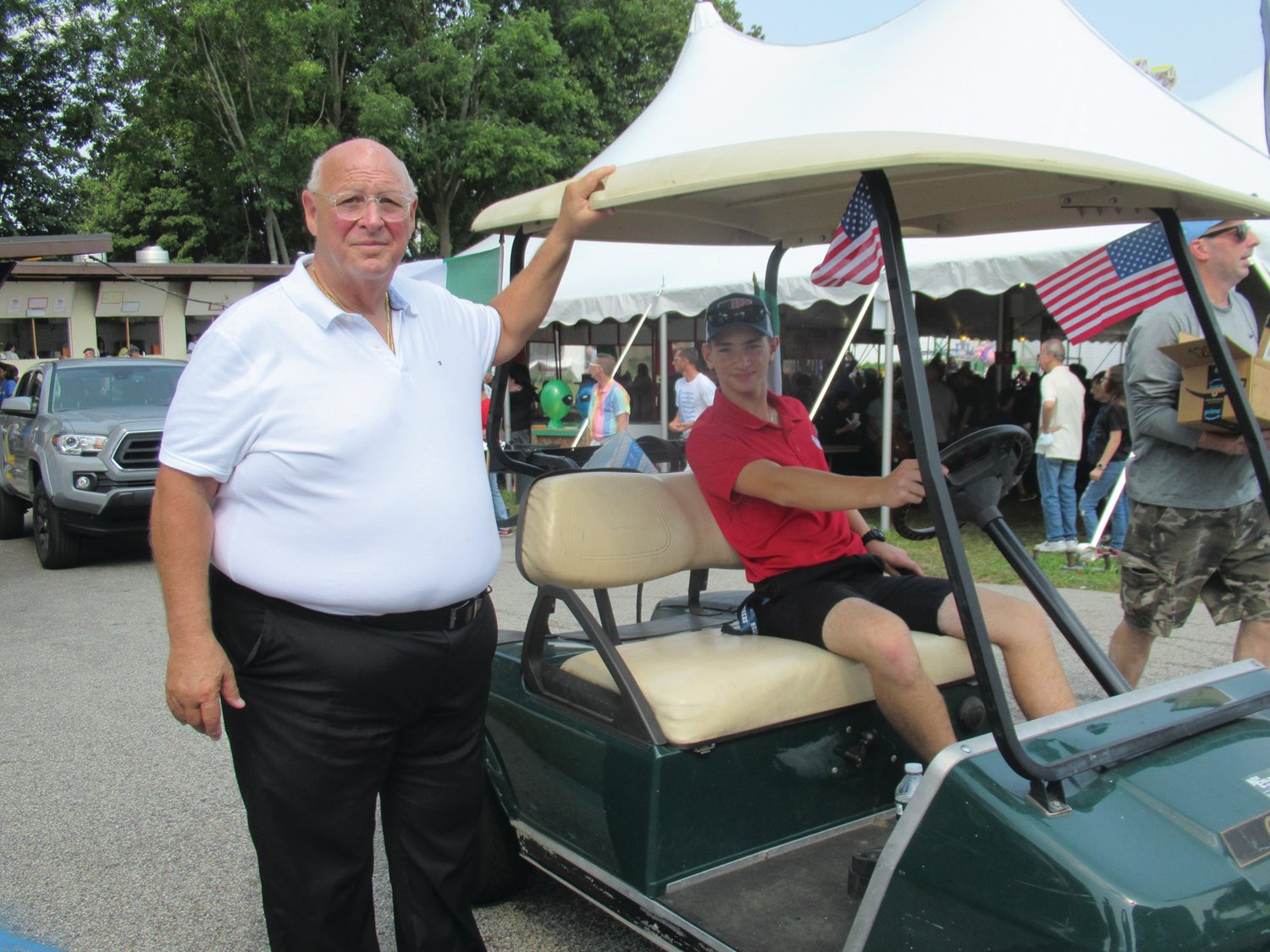 AWESOME ASSIST: Rev. Peter J. Gower made his way around Festival Field either on foot or in this golf cart driven by Nicholas Williams, who performed many duties last week, and provided valuable assistance for older parishioners to get around the grounds.